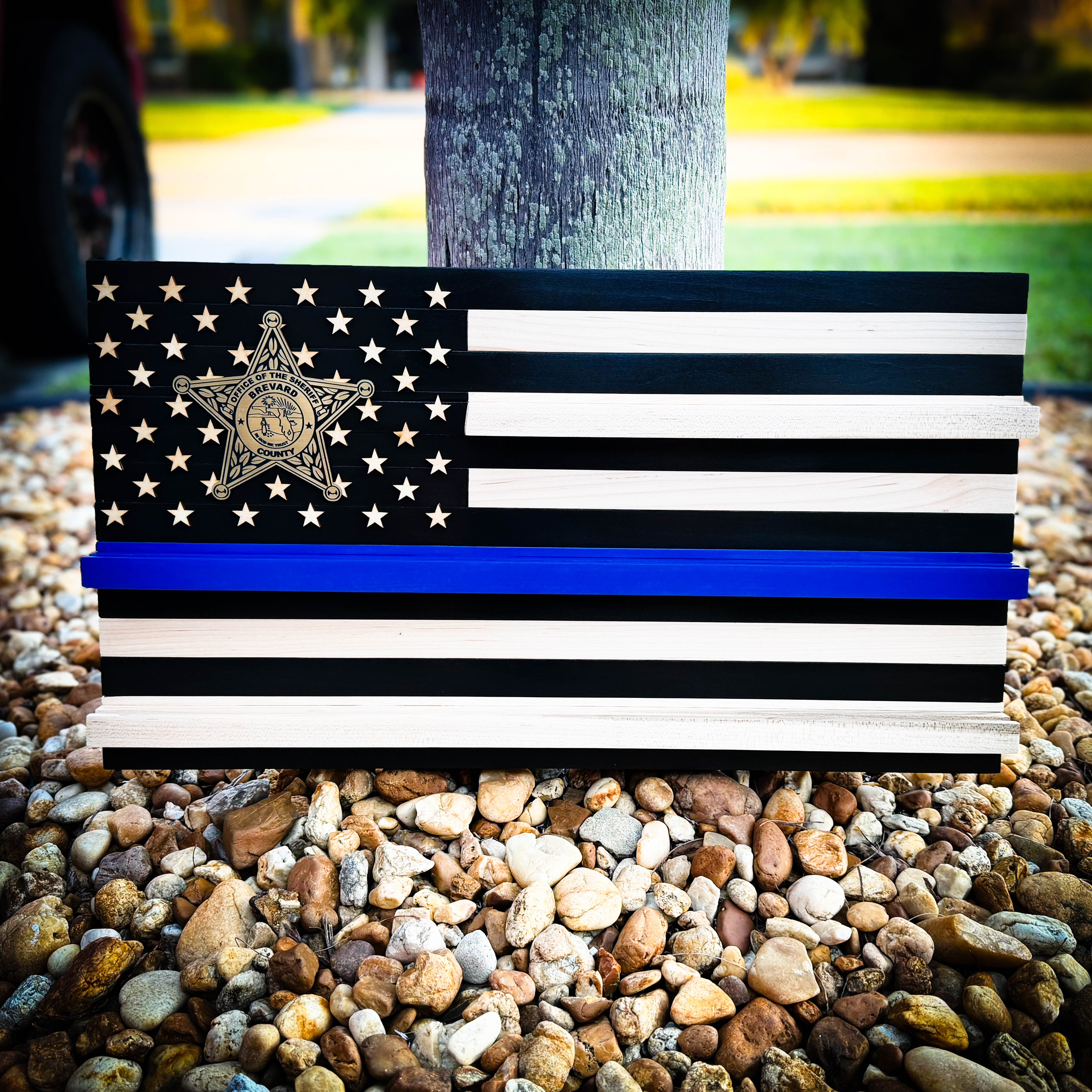 American flag with a blue stripe on a wooden stand outdoors.