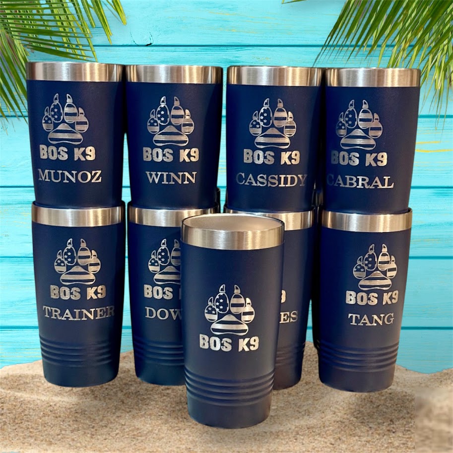 Set of blue tumblers with engraved names against a blue wooden background