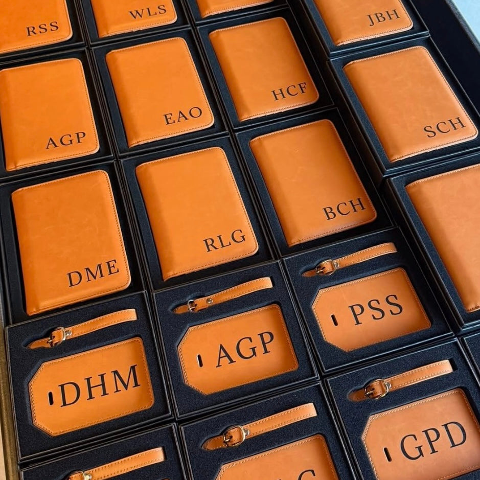 Collection of personalized brown luggage tags with initials in a grid pattern.
