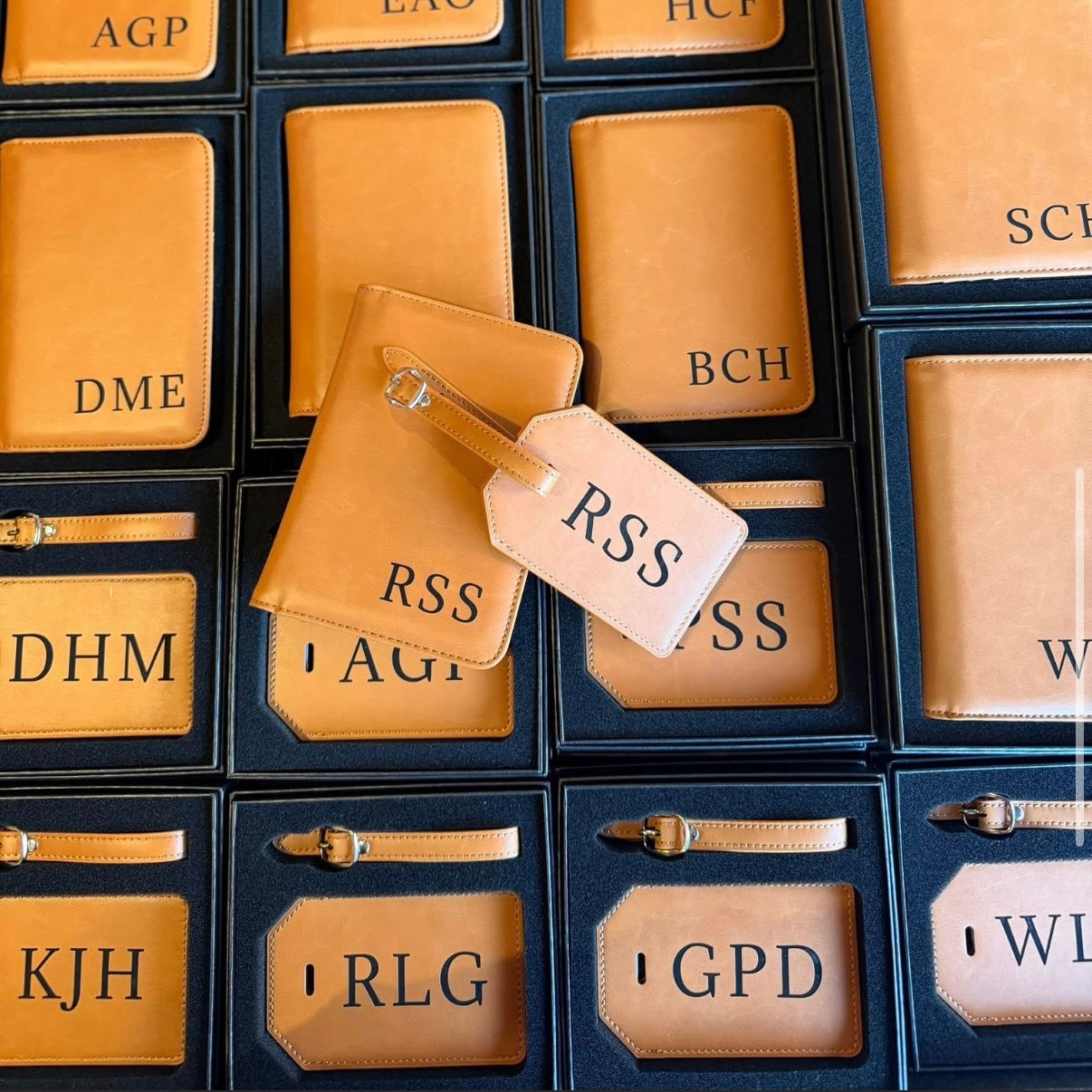 Collection of tan leather luggage tags with initials on a grid pattern