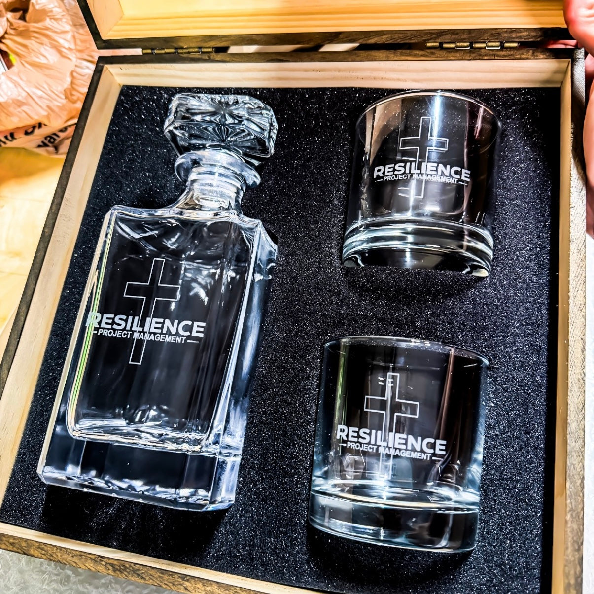 Glass decanter and two glasses with custom business logo in a wooden box.