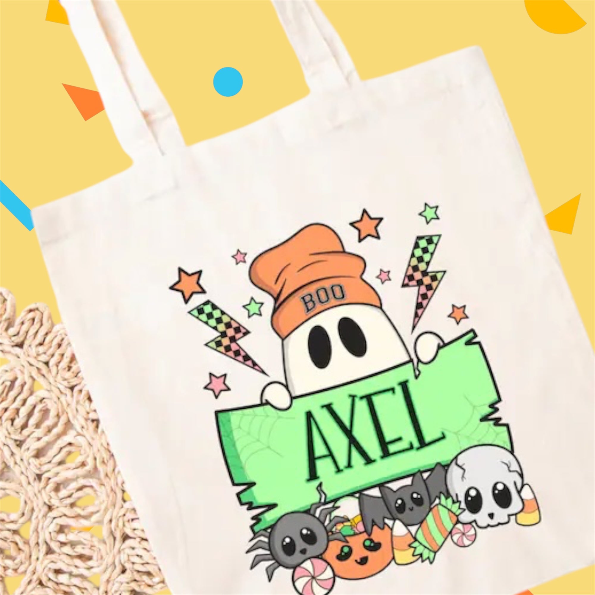 Tote bag with Halloween-themed design featuring a ghost, candy, and text on a yellow background.
